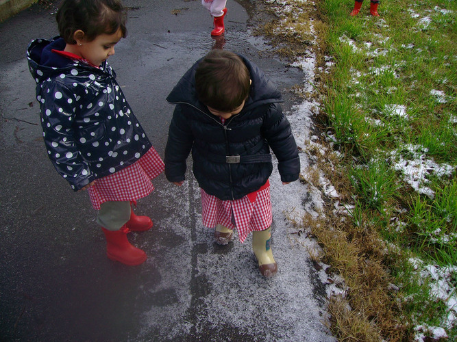 Niños pisando el granizo alojado en el asfalto.