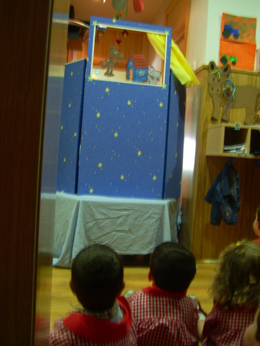 Niños viendo una representación de marionetas.
