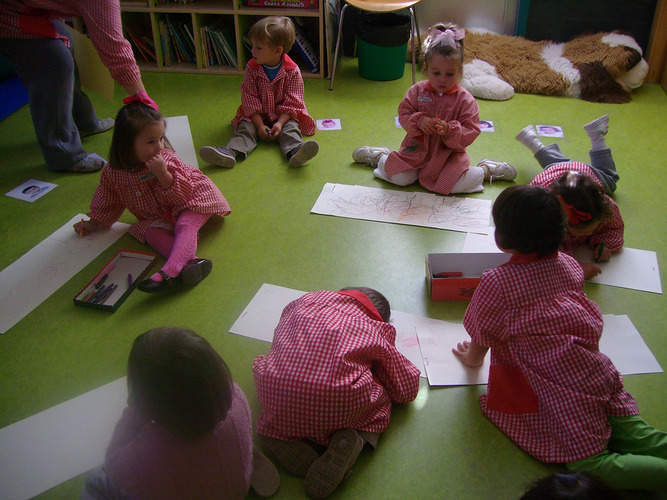 Grupo de niños sentados en el suelo dibujando.