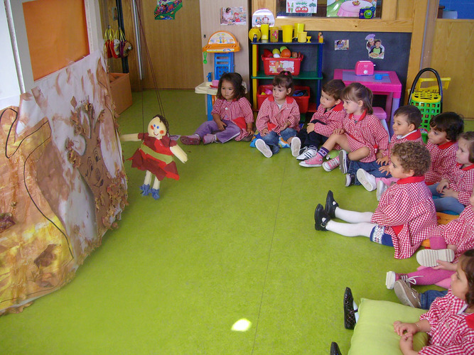 Niños atendiendo a una marioneta que les cuenta un cuento.
