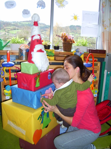 Profesora con un bebé decorando unos regalos.