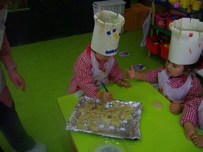 Niños con gorro de cocina decorando los mazapanes.