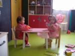 Dos niños sentados en una mesa dentro del colegio