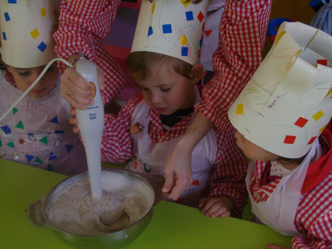 Profesora ayuda a un niño a triturar las castañas con leche, usando la batidora.