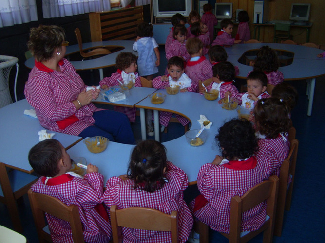 Grupo de niños junto a su profesora, comiendo papilla.