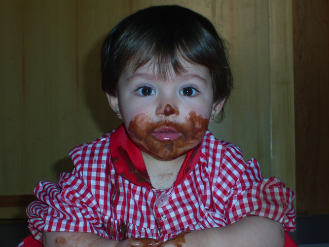 Niña pequeña con la cara manchada de chocolate.