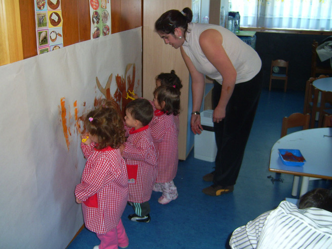 Niños pintando un mural en la pared.