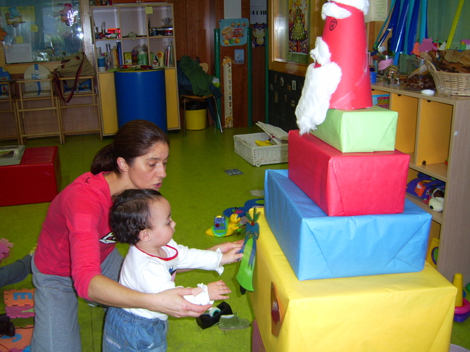 Profesora con niño muy pequeño decorando unos regalos.