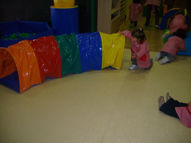 Niños jungango con un tunel de plásticos de colores.