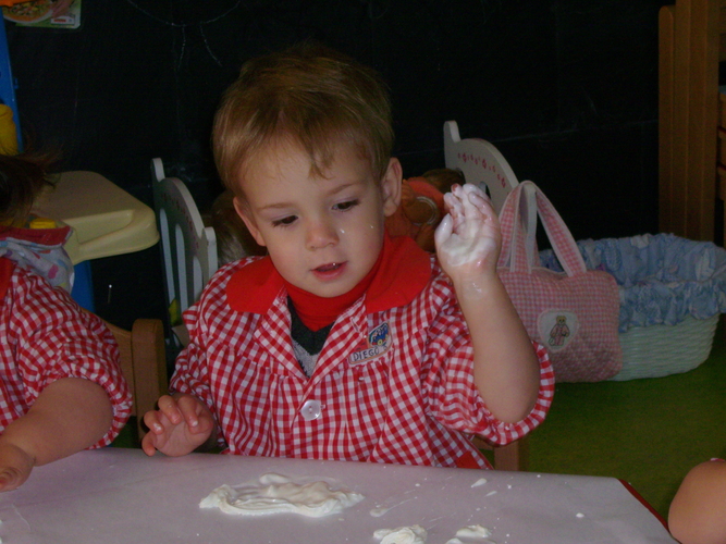 Niño jugando con pintura blanca.