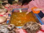 Niños observando un tanque de agua coloreada de naranja