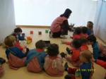 Educadora repartiendo pinturas entre los niños