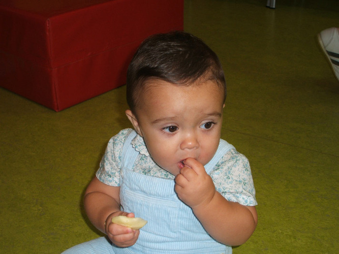Bebé comiendo un trozp de manzana.