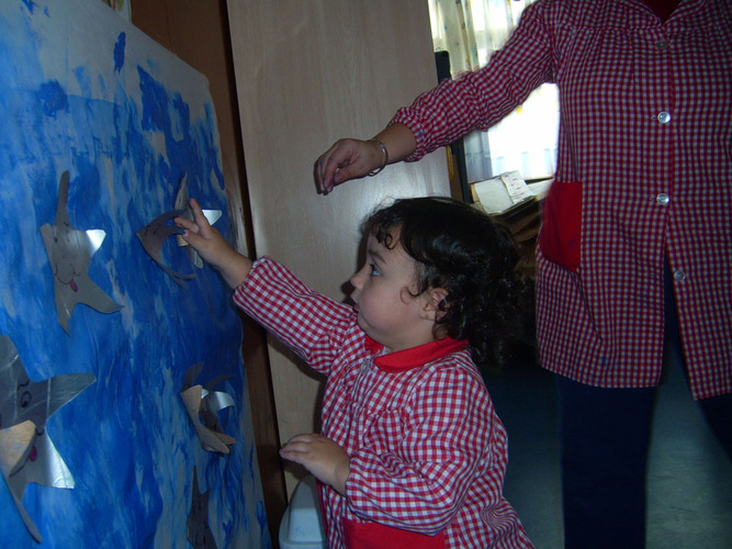 Niño pegando una estrella en un mural de un cielo.