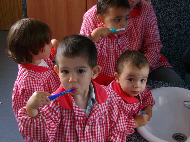 Niños pequeños lavandose los dientes.