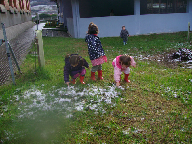 Niños jugando con granizo en un prado.