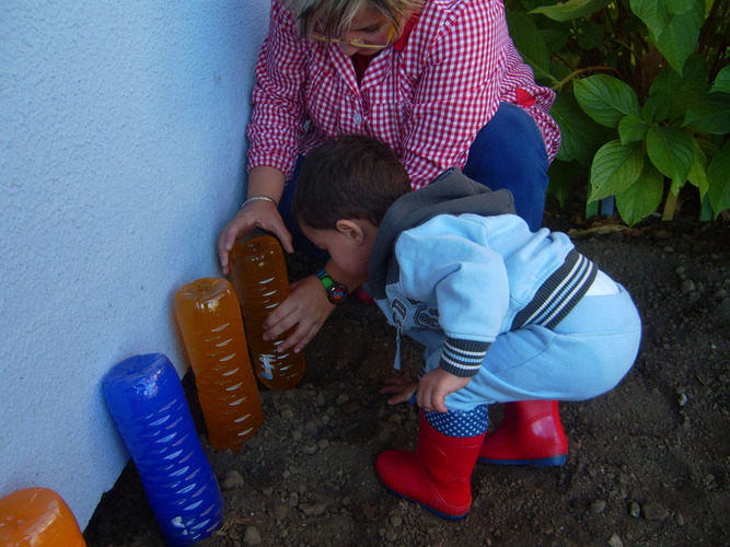 Profesora enseñando a un niño a plantar semillas.