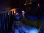 Un niño a oscuras tratando de tocar la luz azul de una linterna