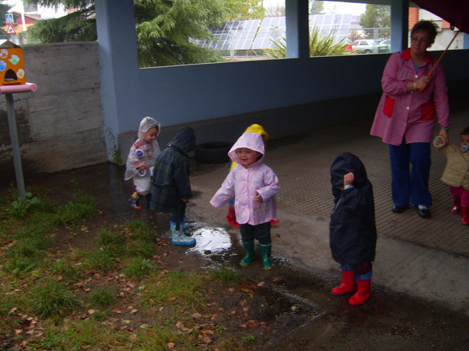 Niños jugando en el exterior vestidos con chubasqueros.