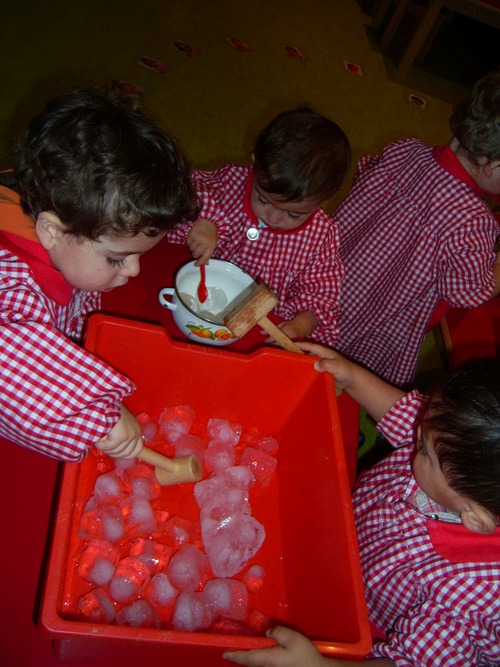 Niños jugando con los hielos de un cubo.