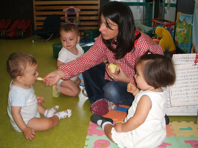 Profesora dandole trocitos de manzana pelada a unos bebés.