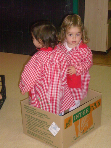 Dos niños metidos en una caja de cartón.