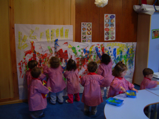 Grupo de niños pintando un mural en la pared.