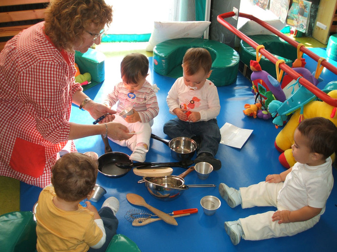 Profesora enseñando utensilios de cocina a unos niños.