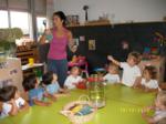 Una educadora repartiendo caramelos a niños sentados en una mesa