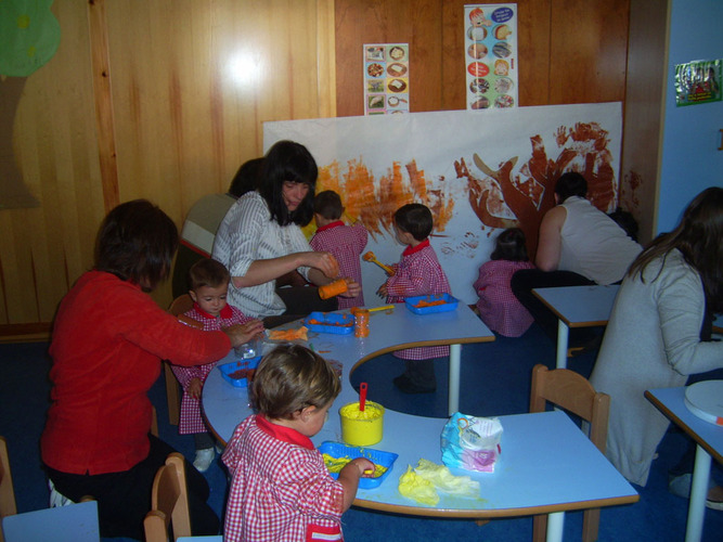 Niños pintando un mural junto con sus profesora.