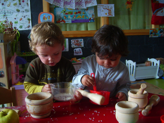Dos niños pequeños jugando con arroz.