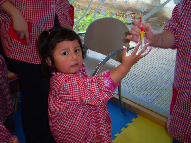 Profesora pintando de blanco la mano de una niña.