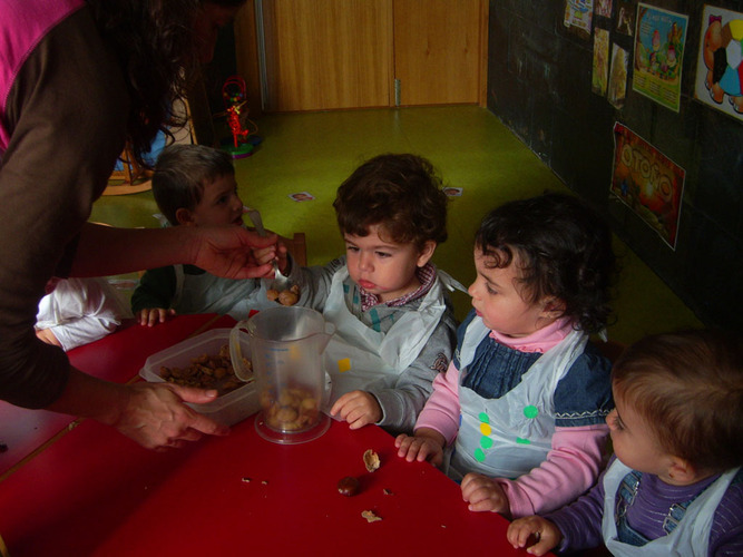 Niños echando frutos secos pelados en un recipiente.