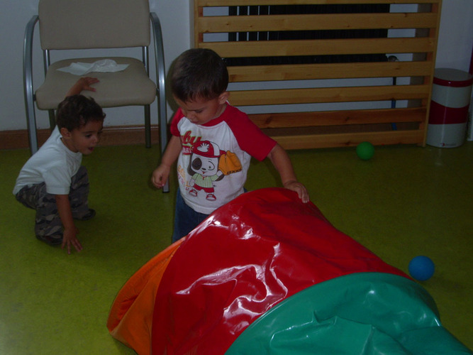 Niños jugando con un túnel de plásticos de colores