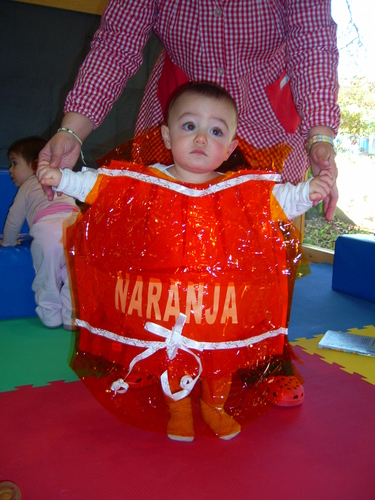 Niño muy pequeño disfrazado de caramelo de naranja.