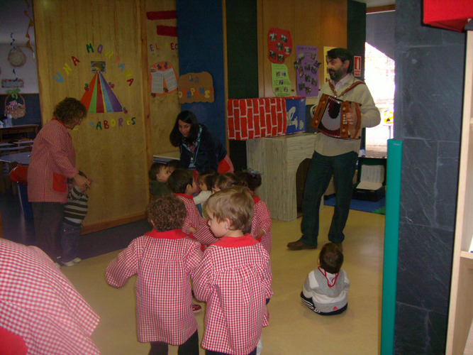 Chico tocando acordeón, mientras los niños bailan.