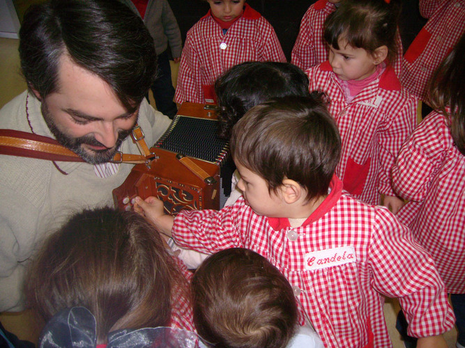 Chico enseñando la acordeón a los niños.