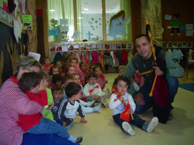 Chico de la gaita arrodillado posando junto a los niños.