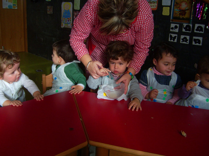 Profesora enseñando a un niño el contenido de un recipiente.