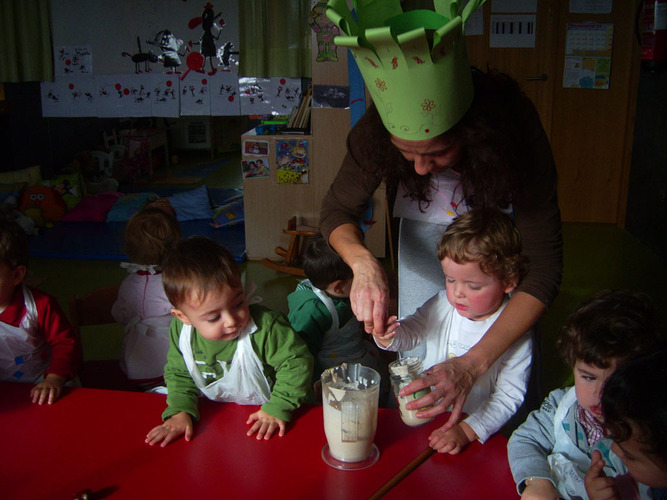 Profesora enseñando a unos niños el resultado del recipiente sobre el que se trituro.