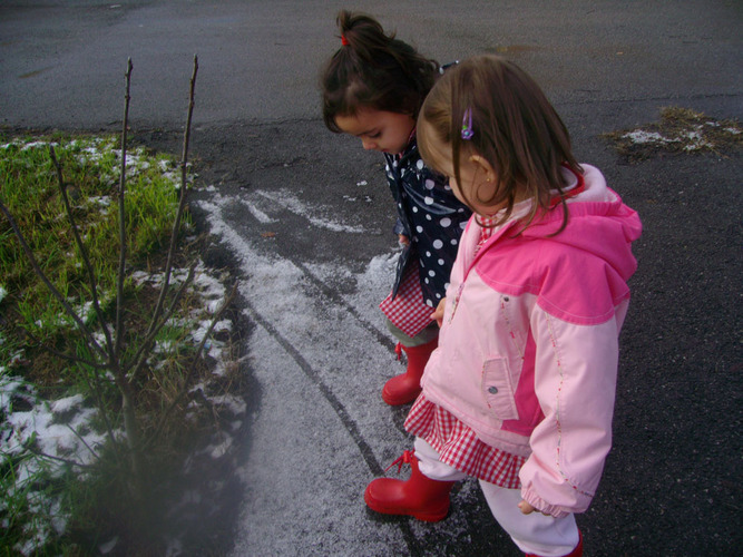 Niñas pisando el granizo alojado en el asfalto.