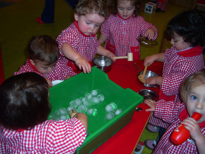 Niños jugando con los hielos de un cubo.