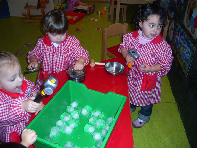 Niñas jugando con los hielos contenidos en un cubo.