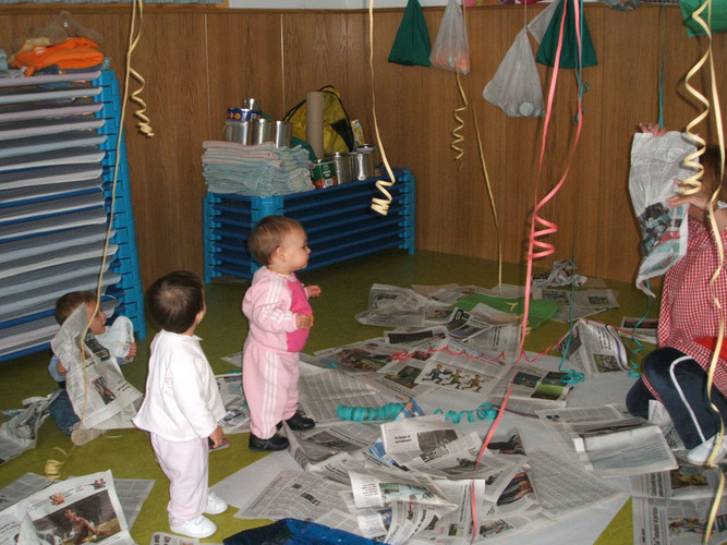 Niños jugando dentre recortes de periodico.