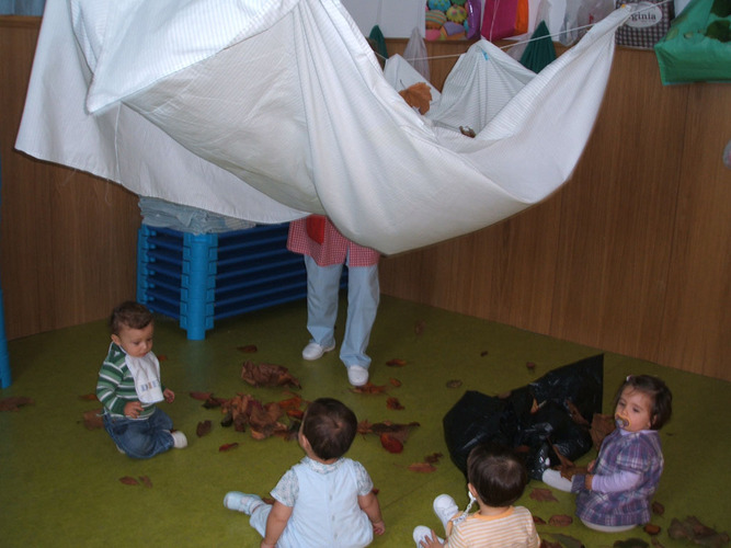 Niños jugando con hojas de árbol secas.