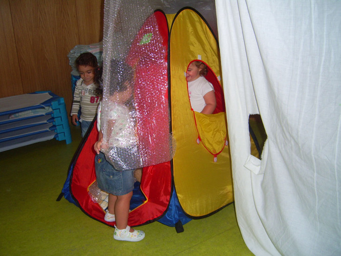 Niños jugando con una tienda de campaña de colores.