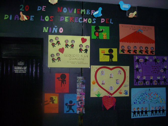 Pared repleta de carteles con corazones, fotos y monigotes.