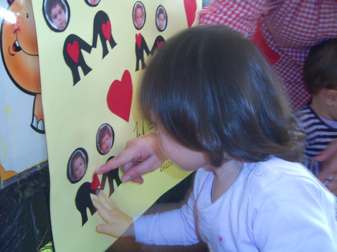 Niña pegando un corazón en un cartel sobre un monigote que tiene su foto.