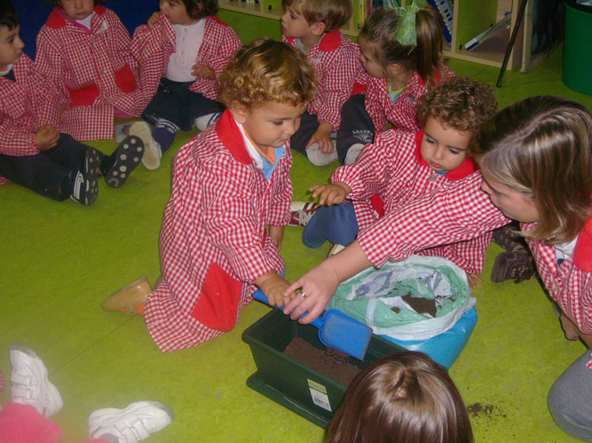 Niños junto a su profesora, jugando con tierra.