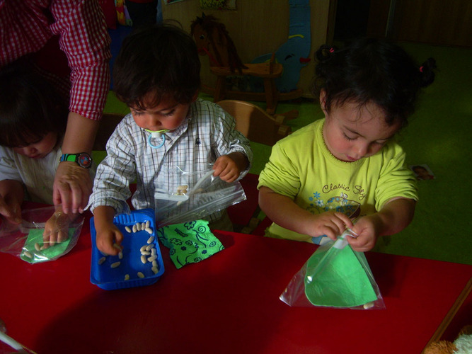 Niños guardando fabas en unas bolsas.